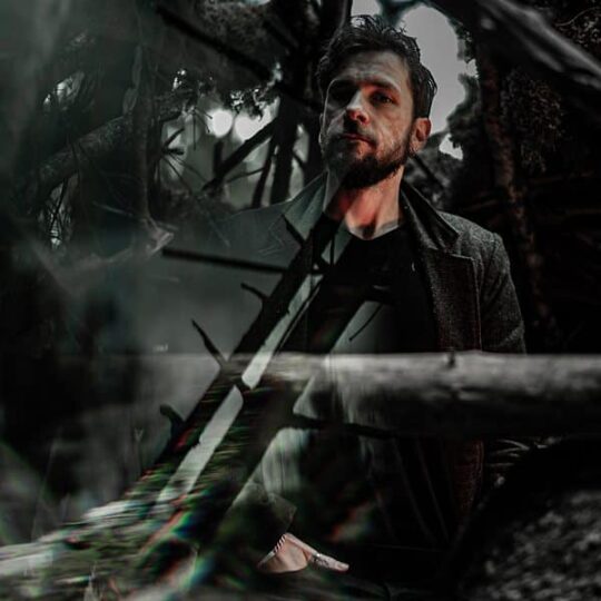 Homme debout dans une forêt sombre et mystique.