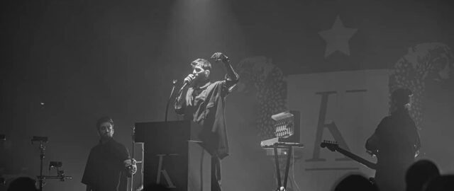 Concert en noir et blanc, chanteur sur scène.