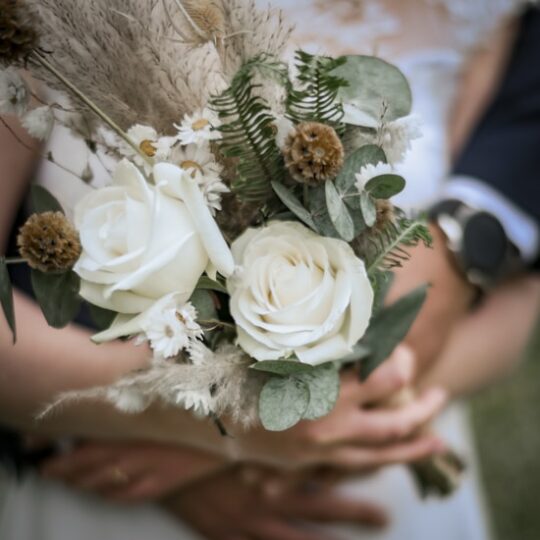 Mains tenant bouquet de mariage avec roses blanches.