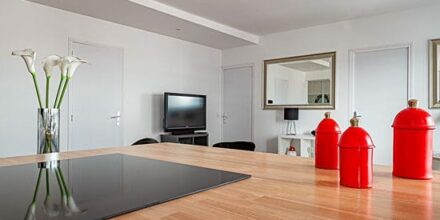 Cuisine moderne avec îlot et décoration rouge.