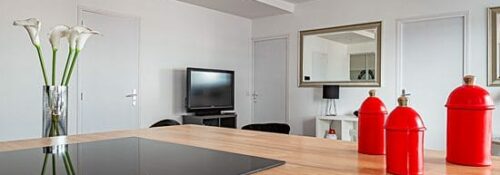 Cuisine moderne avec îlot et décoration rouge.