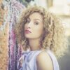 Femme aux cheveux bouclés près d'un mur coloré.