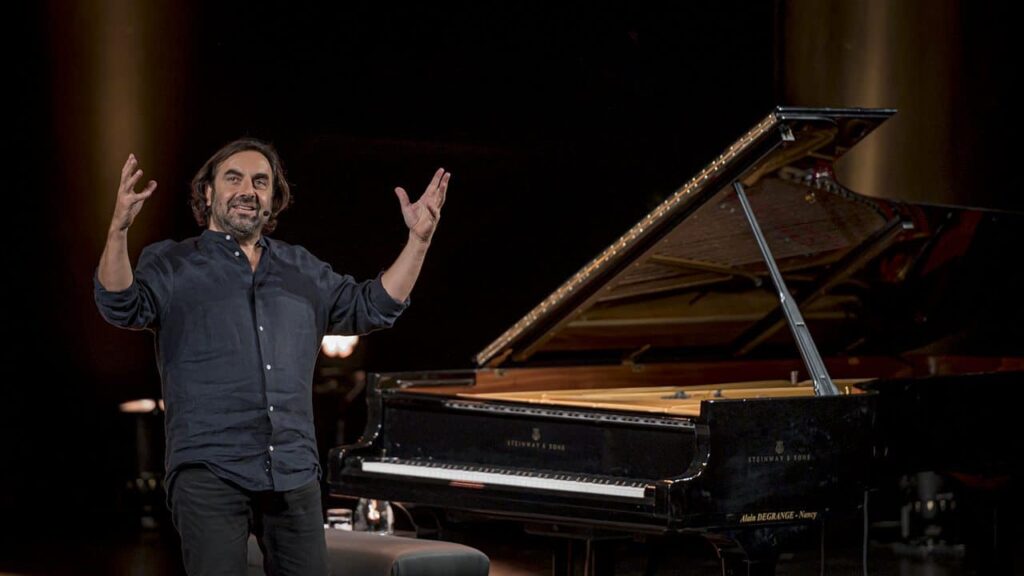 Homme souriant devant un piano à queue.