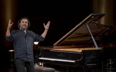 Homme souriant devant un piano à queue.
