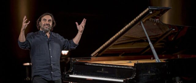 Homme souriant devant un piano à queue.