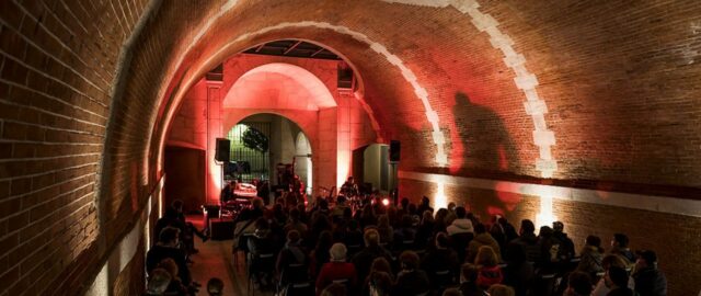 Concert dans une voûte éclairée en rouge.