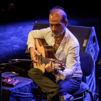 Homme jouant de la guitare sur scène.