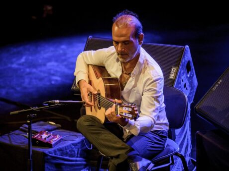 Homme jouant de la guitare sur scène.