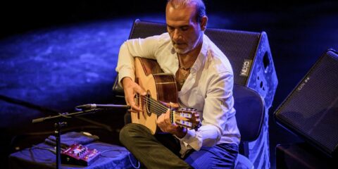 Homme jouant de la guitare sur scène.