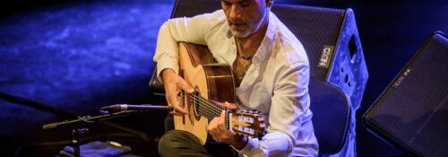 Homme jouant de la guitare sur scène.