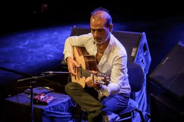 Homme jouant de la guitare sur scène.