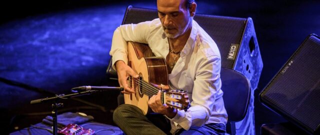 Homme jouant de la guitare sur scène.