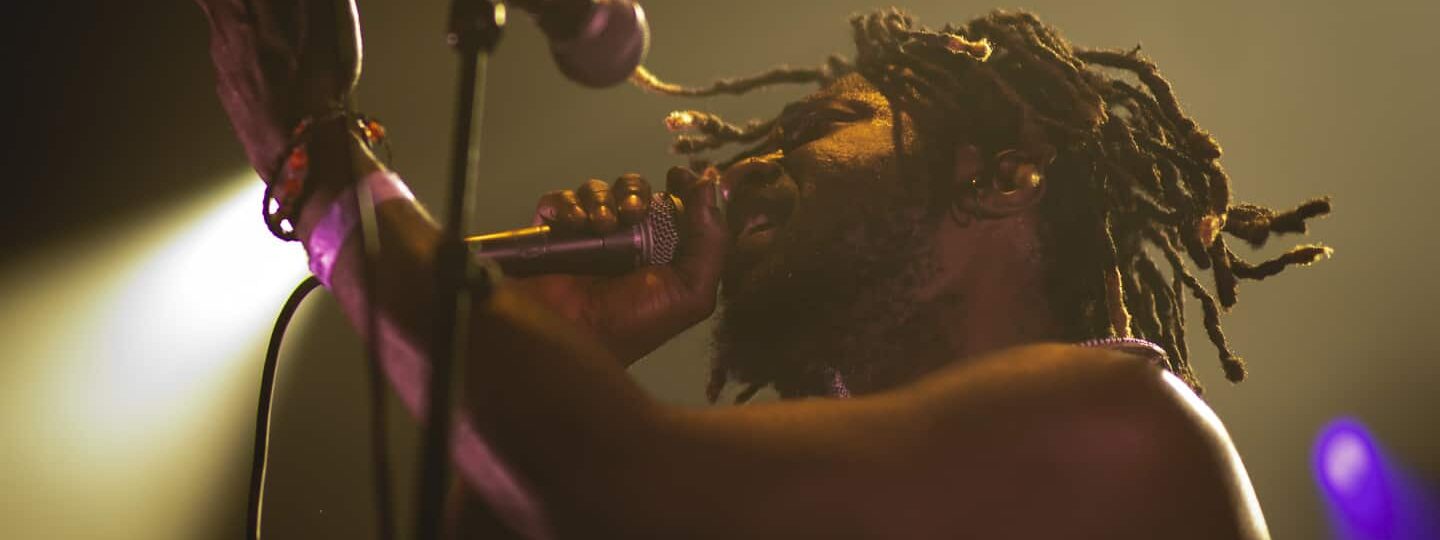 Chanteur sur scène avec micro et projecteurs.
