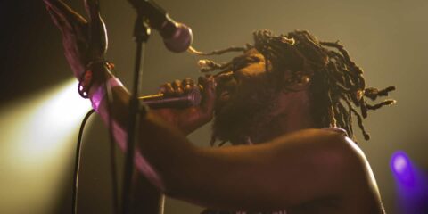 Chanteur sur scène avec micro et projecteurs.