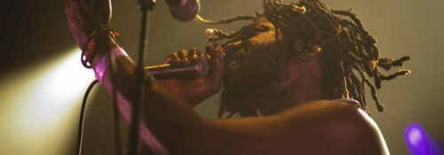 Chanteur sur scène avec micro et projecteurs.