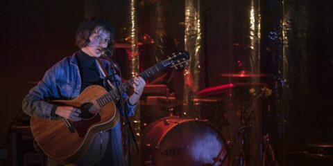 Musicien jouant de la guitare sur scène.