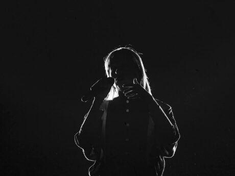 Chanteur silhouette avec microphone sur scène sombre.