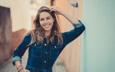 Femme souriante posant dans une ruelle ensoleillée.