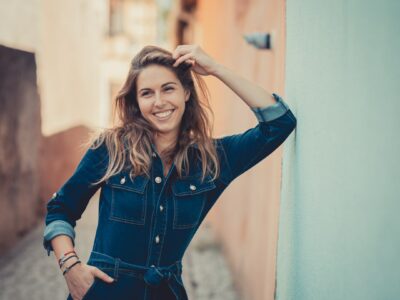 Femme souriante posant dans une ruelle ensoleillée.