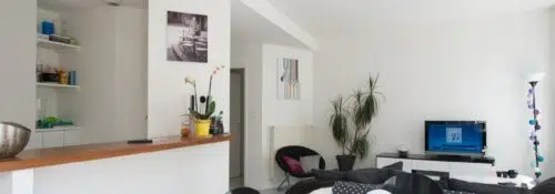 Salon moderne avec cuisine ouverte et télévision.