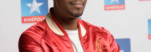 Homme posant devant logo Kinepolis.