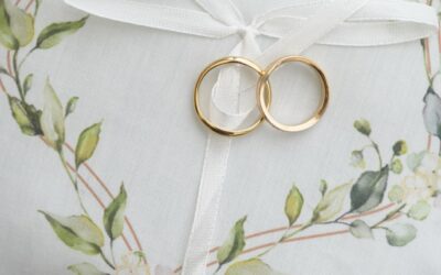 Coussinet blanc avec bagues dorées et décor floral.