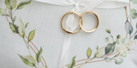 Coussinet blanc avec bagues dorées et décor floral.