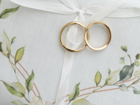 Coussinet blanc avec bagues dorées et décor floral.