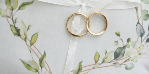 Coussinet blanc avec bagues dorées et décor floral.