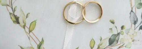 Coussinet blanc avec bagues dorées et décor floral.