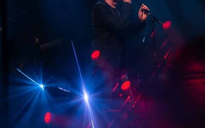 Chanteur sur scène avec éclairage coloré.