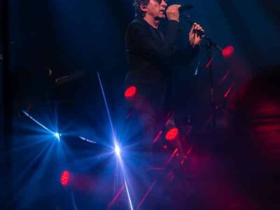 Chanteur sur scène avec éclairage coloré.