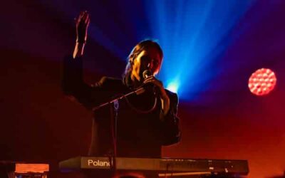 Musicien joue du clavier sur scène illuminée.