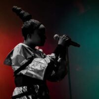 Chanteuse sur scène avec micro et lumières colorées.