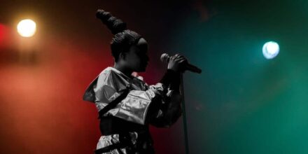 Chanteuse sur scène avec micro et lumières colorées.
