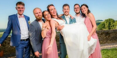 Mariage : amis portant la mariée souriante.