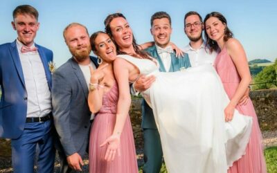 Mariage : amis portant la mariée souriante.
