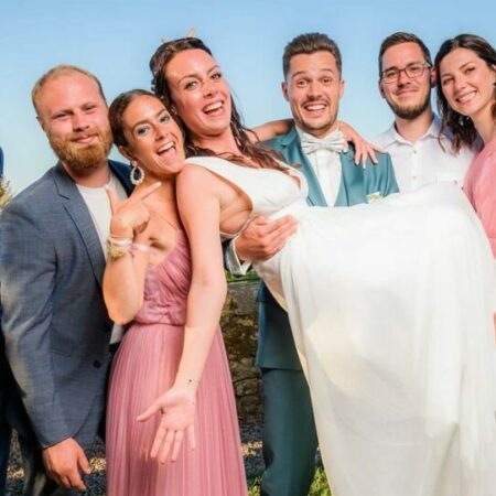 Mariage : amis portant la mariée souriante.