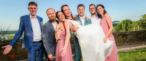 Mariage : amis portant la mariée souriante.