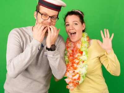 Deux personnes souriantes posent devant un fond vert.