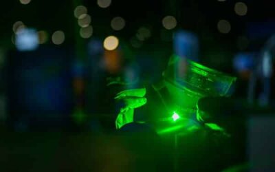 Main tenant un laser vert, lumière réfléchissante.