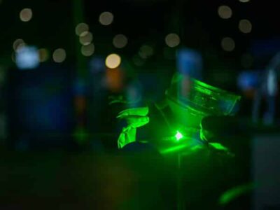 Main tenant un laser vert, lumière réfléchissante.