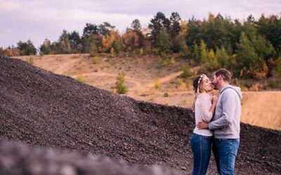Couple s'embrassant devant un paysage boisé.