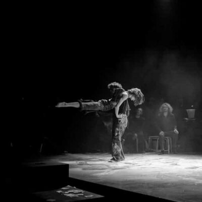 Duo de danseurs sur scène, lumière tamisée.