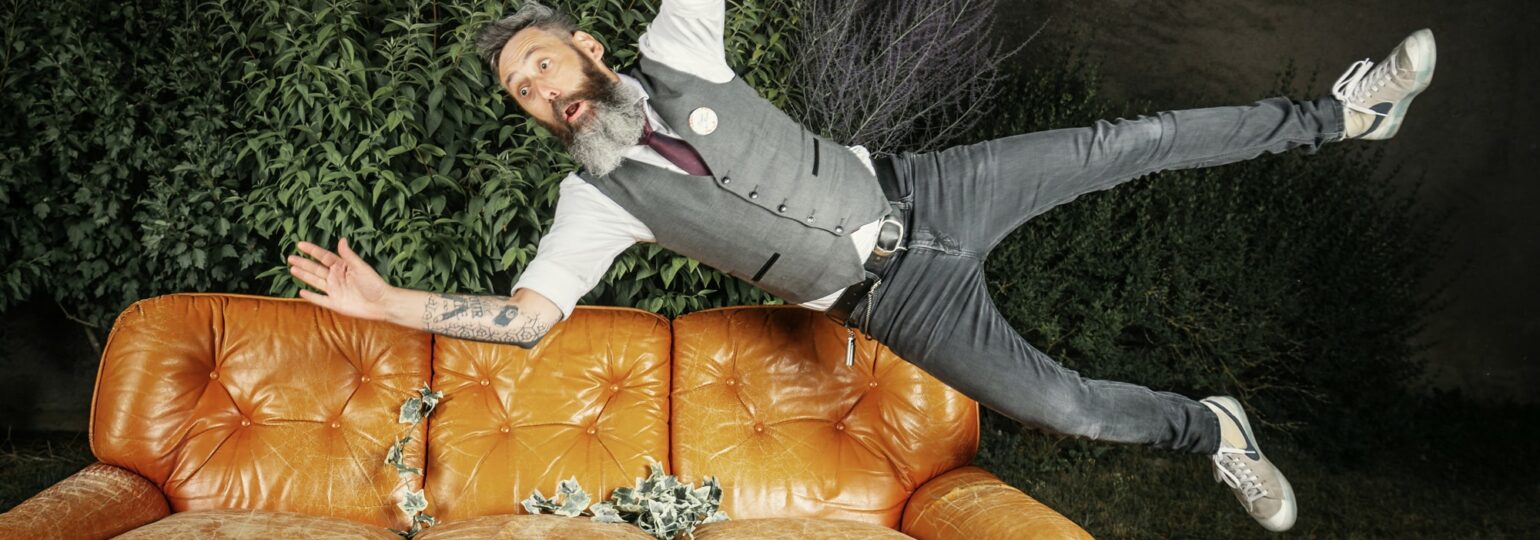 Homme sautant au-dessus d'un canapé en cuir
