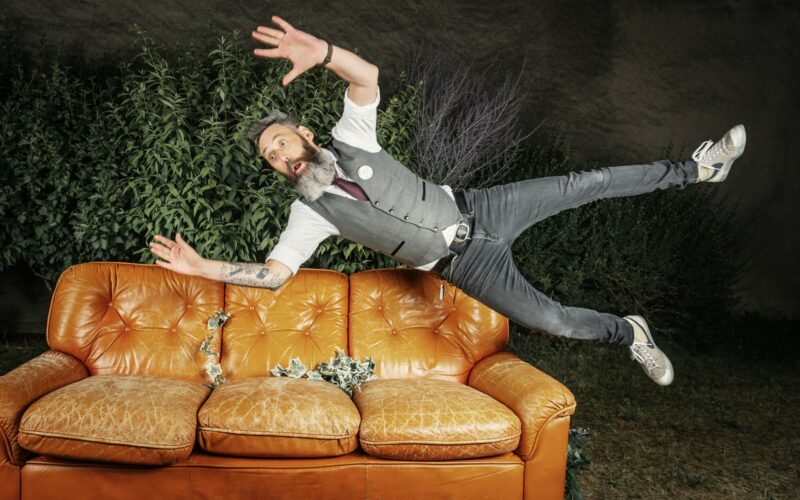 Homme sautant au-dessus d'un canapé en cuir