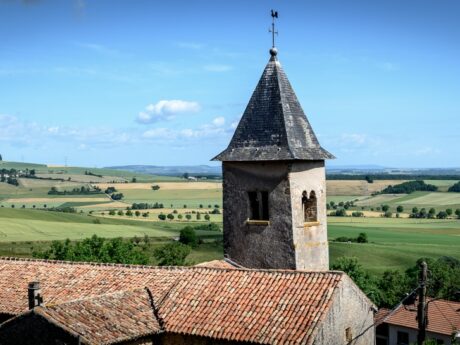 Église et campagne vallonnée sous ciel bleu.