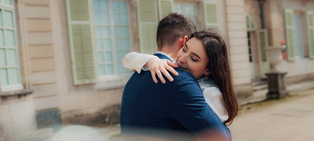 Couple s'enlaçant devant un bâtiment ancien.