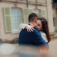Couple s'enlaçant devant un bâtiment ancien.