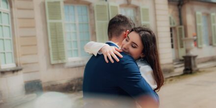Couple s'enlaçant devant un bâtiment ancien.